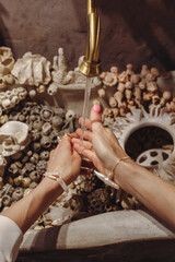 Young woman washes hands at seashell-decorated washbasin with fashionable pearls in a bright space