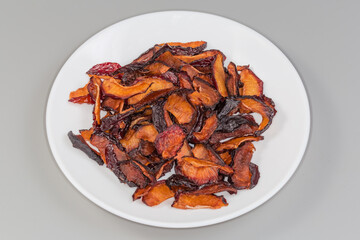 Dried plums slices on plate on a gray background