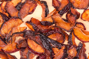Dried plums slices on wooden surface, top view close-up