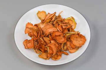 Dried sliced apples on dish on a gray background