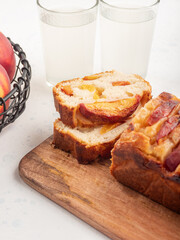 Peach cake loaf on wooden cutting board on white backgroud