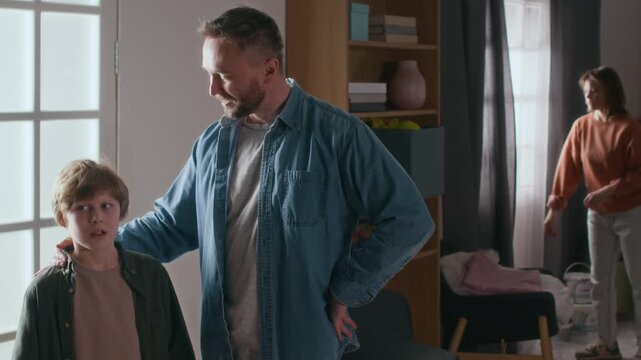 Father talking to his little son about future interior design of their new apartment, while mother checking curtains after their recent relocation