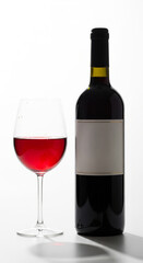 A bottle of wine next to a filled glass of wine on a clean background, product presentation concept