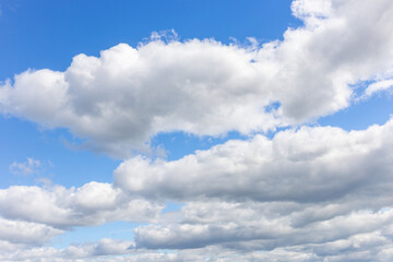 Obraz premium White clouds on a summer blue sky for background or wallpaper design. Majestic cumulus clouds float across the endless sky, their graceful forms painting a mesmerizing canvas of beauty and grandeur.