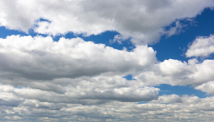 White clouds on a summer blue sky for background or wallpaper design. Majestic cumulus clouds float across the endless sky, their graceful forms painting a mesmerizing canvas of beauty and grandeur.