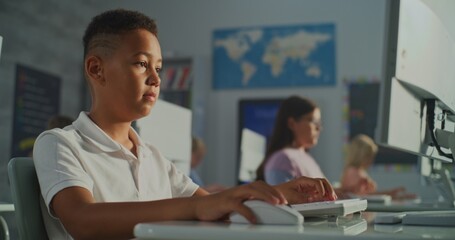 Schoolchildren Working at Computers in Bright Classroom. Schoolboy Looking Intently at Screen and Typing. Concept Modern Primary Education, Interactive Learning, and Skill Development. Handheld.