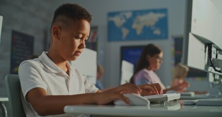 Schoolchildren Working at Computers in Bright Classroom. Schoolboy Looking Intently at Screen and Typing. Concept Modern Primary Education, Interactive Learning, and Skill Development. Handheld.