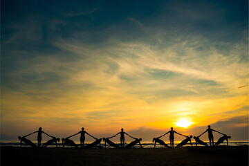 Sunrise over the beach with silhouettes practicing yoga