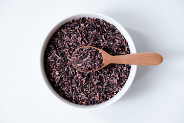 A bowl of black sticky rice grains isolated on white background