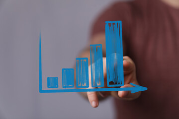 Business growth, success, progress concept.  Hand interacts with upward trending bar chart.