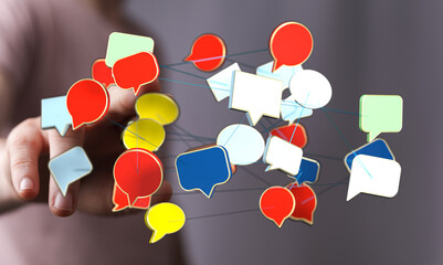 Digitally connected speech bubbles hover above a persons hand representing social media networks and digital communication.