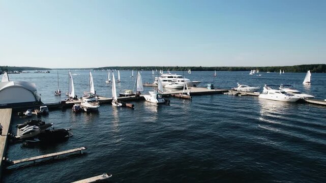 Yachts and speedboats are moored on the lake. Odis move from small waves on the water. Shooting in motion from the air