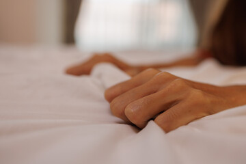 Close up woman hands grasping the blanket in the moment of sexual pleasure or orgasm. Ecstasy. Sex...
