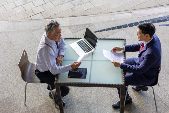 Two generations of business professionals in a modern setting conduct a recruitment interview, highlighting young talent, mentorship, and intergenerational collaboration for success.