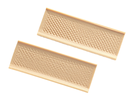 Two rectangular, beige objects, textured, lying at an angle against a black backdrop