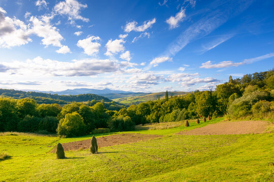 countryside landscape of transcarpathia on september evening. village in the valley and rural fields on the forested hills. carpathian mountain ridge with pikui peak in the distance