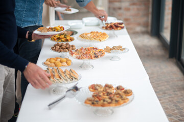 Elegant gathering enjoying a diverse buffet selection at an exclusive private event with colleagues friends and family celebrating an occasion with delicious food spread out on a long table