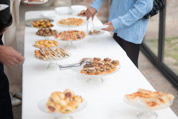 People enjoying a diverse selection of delicious food at a sophisticated private event buffet spread with various appetizers and main courses on a long table