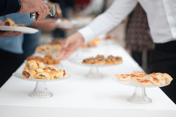 Elegant gathering of guests enjoying a delicious buffet spread at a private event serving a variety of appetizers and finger foods for guests to select from the table