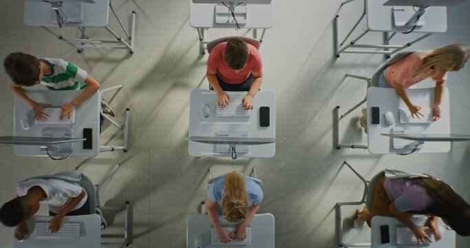 Children Typing on Keyboards in Computer Lab. Kids Studying at Computers in Bright Computer Lab, Learning Technology and Developing Computer Skills. Concept of Modern Education. Top View. Static Shot.