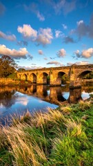 Obraz premium Picturesque stone bridge over a calm river at sunset