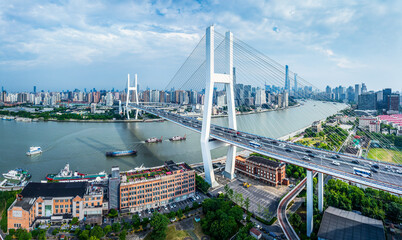 Aerial view of a modern cable stayed bridge with traffic over a river and the city skyline in...