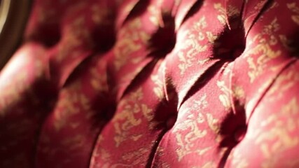 Elegant, tufted cushion close-up showcasing red and gold floral pattern with shadowed folds. Texture emphasizes the plush details - Powered by Adobe