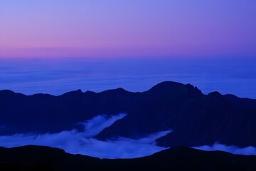 Purple and blue mountain range at dusk with clouds and a gradient sky landscape view scene