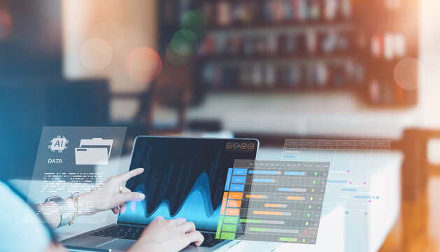 Businesswoman using AI data analytics and digital project management tools on laptop.Hand pointing on laptop screen in modern workplace technology for data-driven decisions and productivity planning.