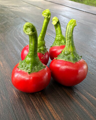 A closeup composition of 4 hot red peppers the size of cherries