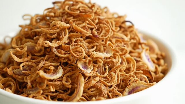 Close Up of Crispy Fried Onion Strings in White Bowl on White Background