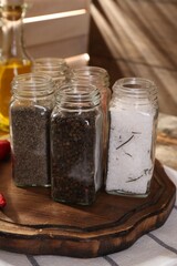Different aromatic spices in glass jars on table, closeup