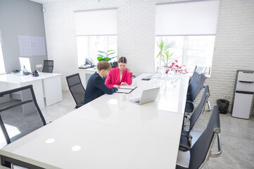 Man and woman talking while sitting at desk in office. 