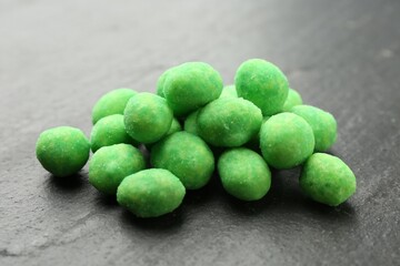 Pile of delicious wasabi coated peanuts on dark textured table, closeup