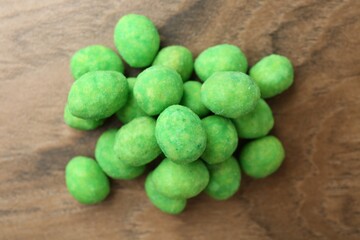 Pile of delicious wasabi coated peanuts on wooden table, flat lay