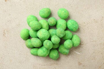 Pile of delicious wasabi coated peanuts on grey textured table, flat lay