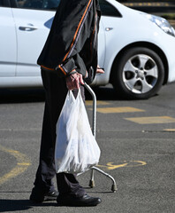 Old man walks on the street with a walker