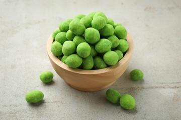 Wasabi coated peanuts in bowl on light table, closeup