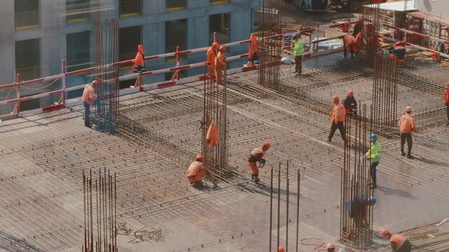Construction workers reinforcing concrete floor of high rise building