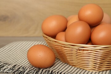 Raw chicken eggs in wicker basket on countertop, closeup