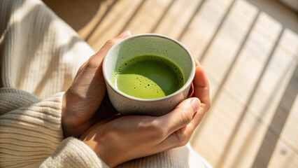 A person is drinking hot matcha tea from a cup, perhaps during a morning break