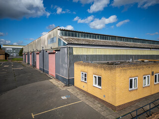 Fototapeta premium Modern warehouse and distribution depot seen from above with metal cladding, parking bays and surrounding trees in industrial estate on bright sunny day