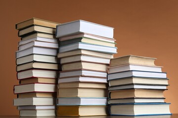 Fototapeta premium Stacks of many books on table against light brown background, low angle view
