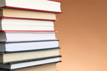 Stack of many books against light brown background, closeup. Space for text