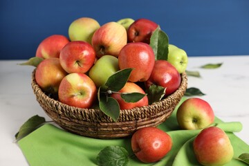 Fresh ripe apples in basket on white table, closeup