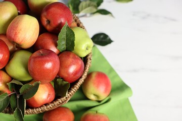 Fresh ripe apples in basket on white table, closeup. Space for text