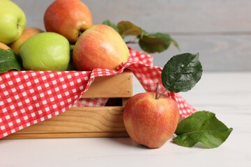 Fresh ripe apples in crate on white table, closeup