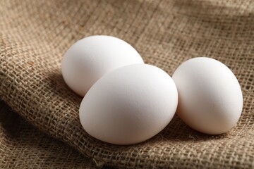 Raw chicken eggs on burlap cloth, closeup