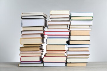 Many stacked books on table against light grey background