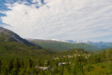 Amazing landscape of the Norwegian country during a perfect summer holiday with wonderful green fields, perfect cloudscape and breath-taking panoramic view as far as you can see with mountains and fjo